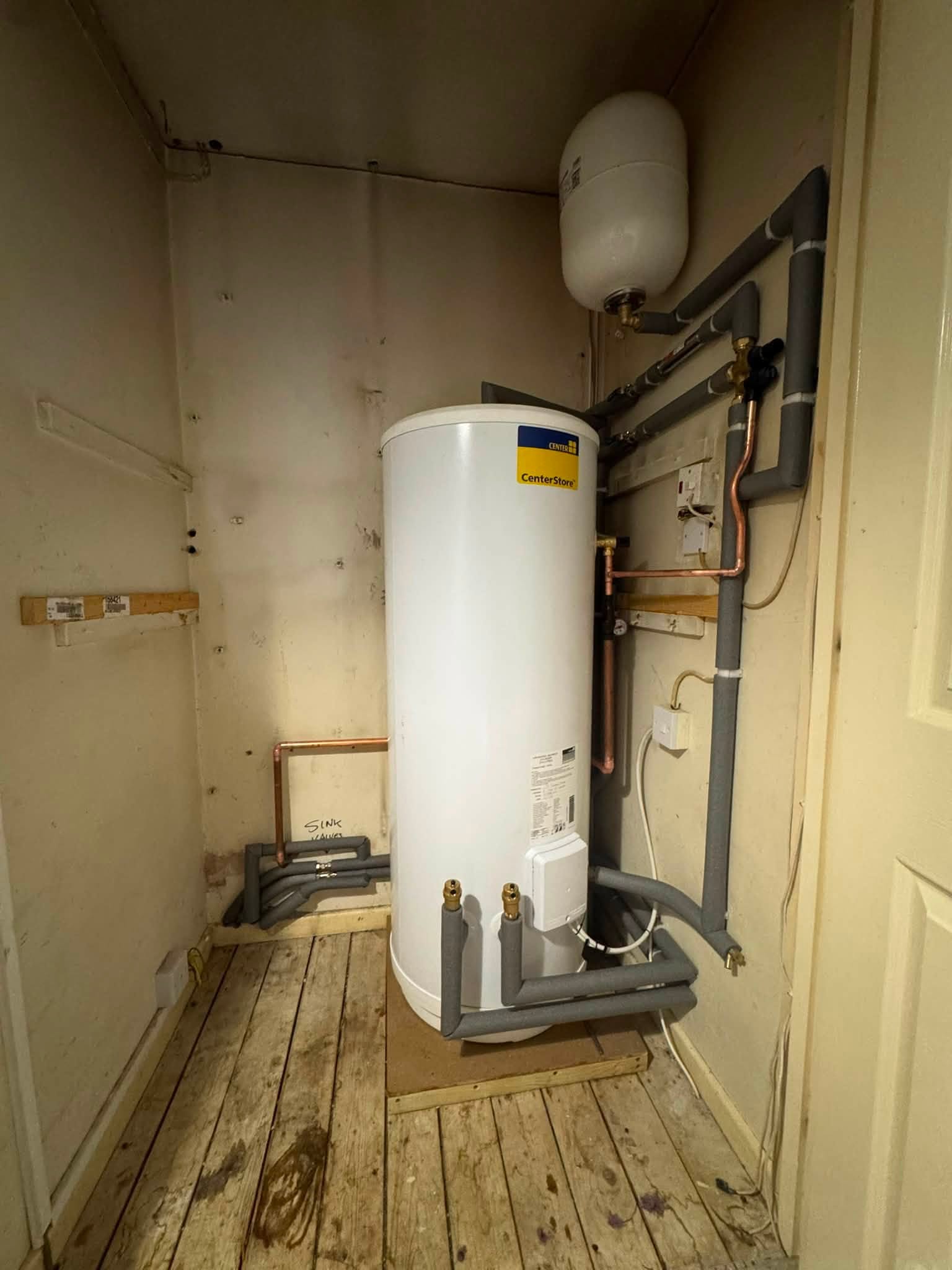 After: a new pressurised hot water cylinder and expansion vessel in the same cupboard