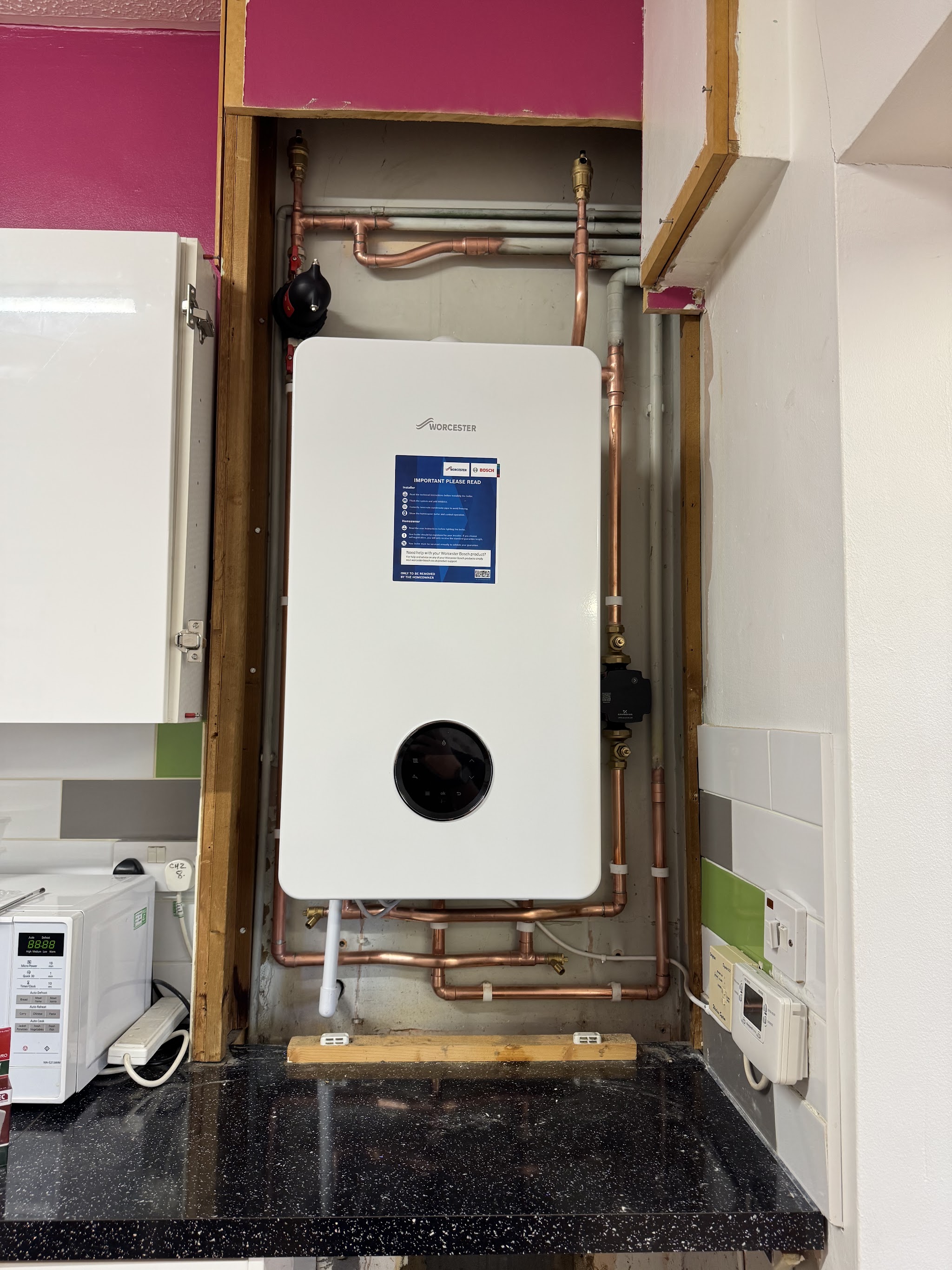 New wall-hung boiler with copper pipework fitted in a kitchen alcove
