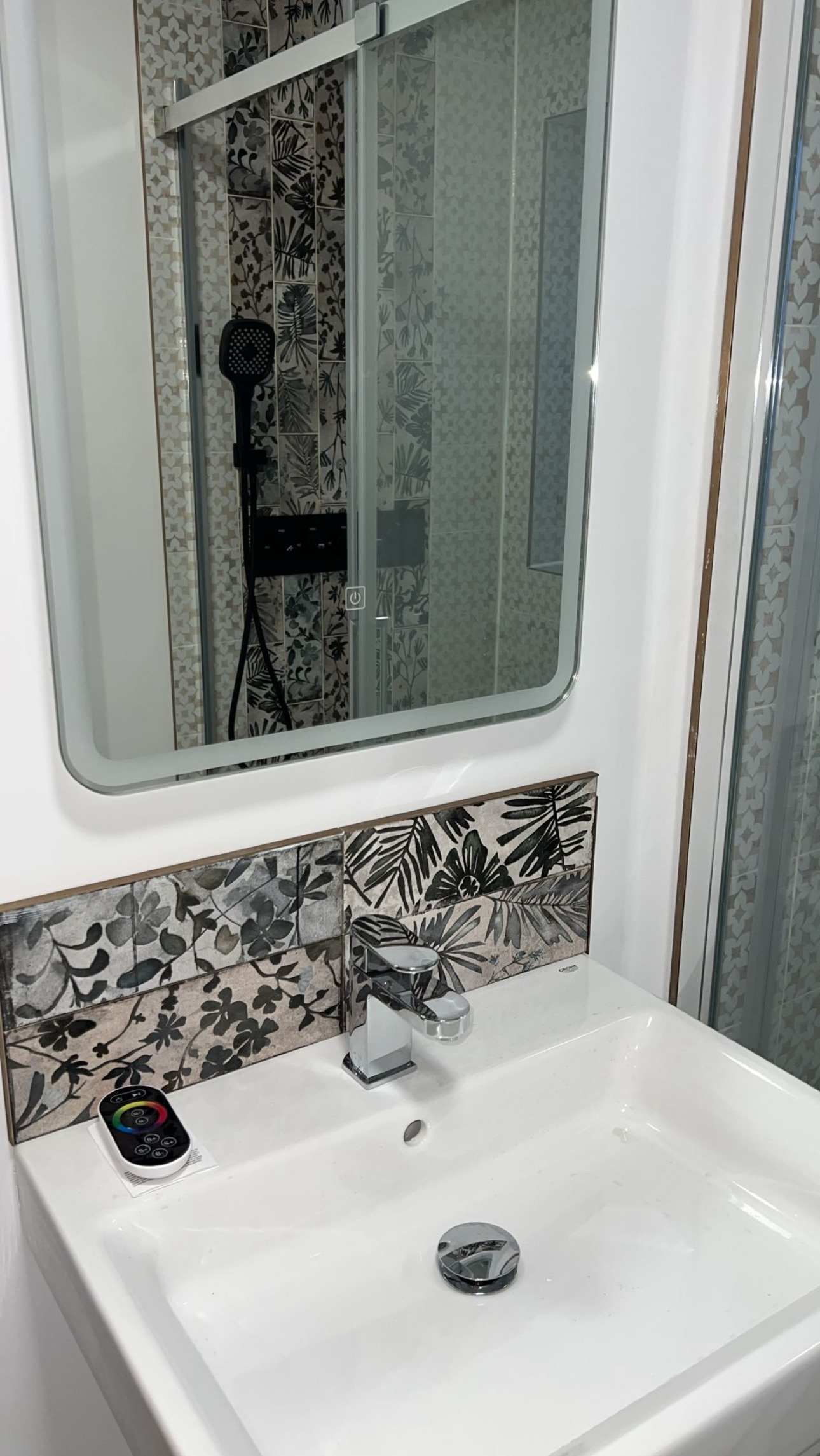 New bathroom basin with a patterned tile splashback and an illuminated mirror