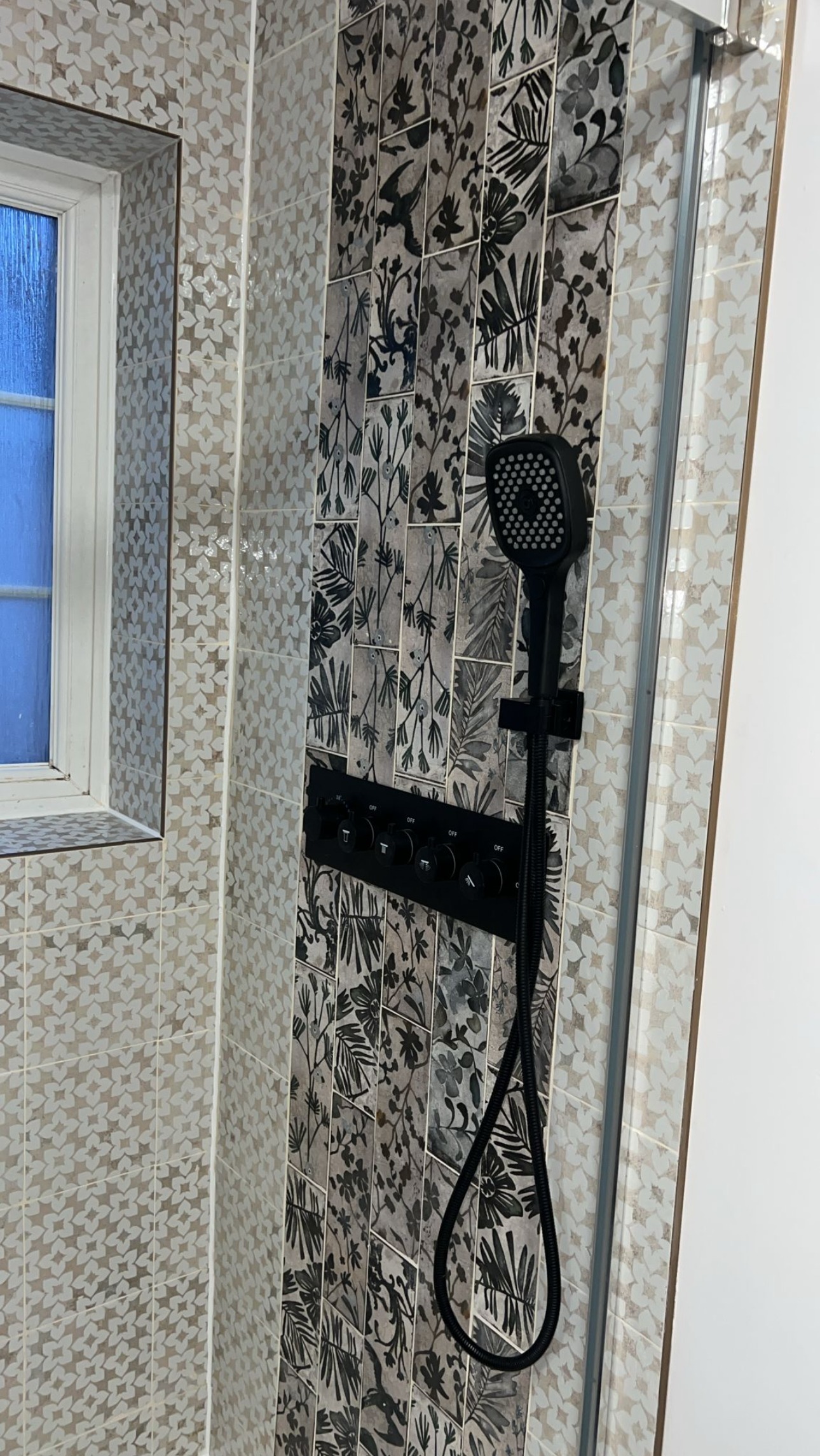 New shower with a black rail shower set against patterned feature tiles